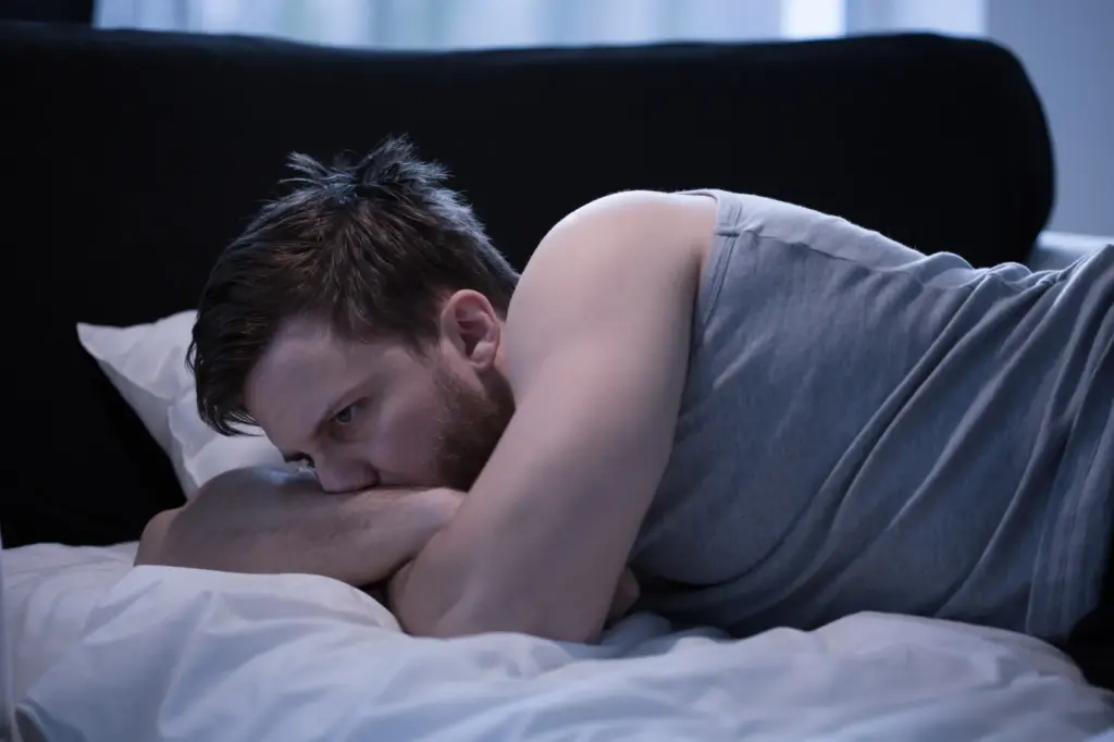 Mann liegt nachdenklich im Bett und wirkt emotional belastet nach einem Vertrauensbruch