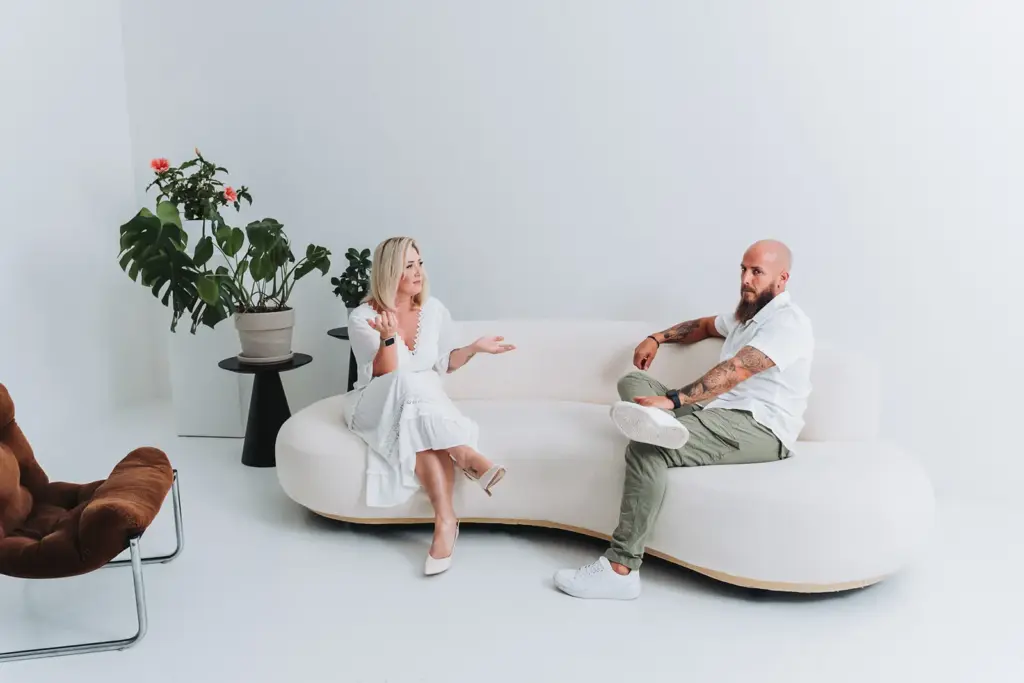 Frau und Mann sitzen mit Abstand auf einem Sofa und sprechen miteinander